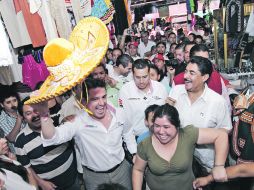 Aristóteles Sandoval saluda con el sombrero entre locatarios de San Juan de Dios.  /