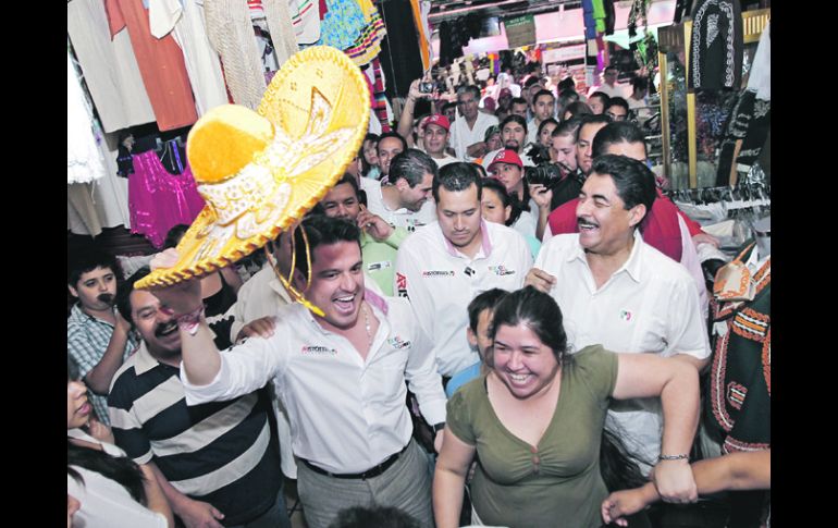 Aristóteles Sandoval saluda con el sombrero entre locatarios de San Juan de Dios.  /