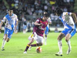 El volante de Tecos Rubens Sambueza (14) conduce el esférico ante la marca del defensor poblano Lacerda (d) y del mediocampista Pineda.  /