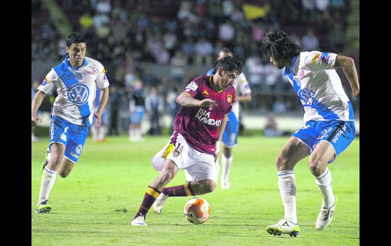 El volante de Tecos Rubens Sambueza (14) conduce el esférico ante la marca del defensor poblano Lacerda (d) y del mediocampista Pineda.  /