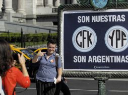 Una mujer posa para una foto junto a un fiche de apoyo a la expropiación de la petrolera YPF. EFE  /