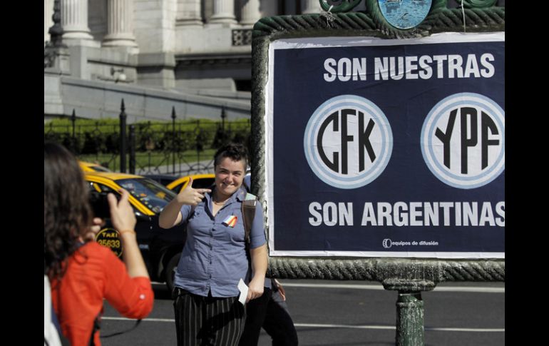 Una mujer posa para una foto junto a un fiche de apoyo a la expropiación de la petrolera YPF. EFE  /