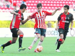 Carlos Fierro trata de avanzar en medio de dos zagueros rojinegros, durante el partido de ayer en el Omnilife.  /