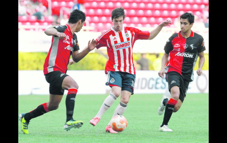 Carlos Fierro trata de avanzar en medio de dos zagueros rojinegros, durante el partido de ayer en el Omnilife.  /