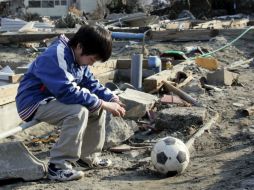 En la pelota está escrito ''¡Ánimo Misaki Murakami!''. En la imagen un pequeño con su balón tras el devastador suceso. ARCHIVO  /