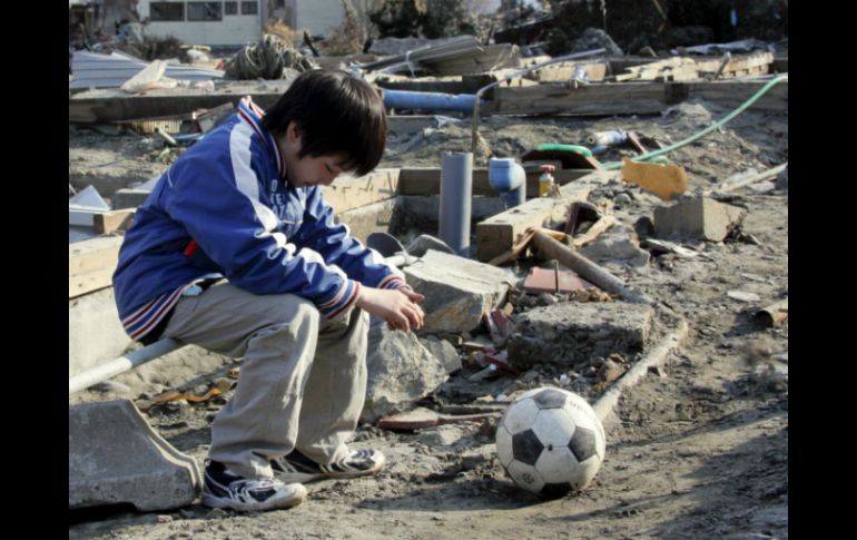 En la pelota está escrito ''¡Ánimo Misaki Murakami!''. En la imagen un pequeño con su balón tras el devastador suceso. ARCHIVO  /