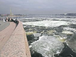 Varias personas observan los bloques de hielo que bajan por el cauce del Río Neva. EFE  /