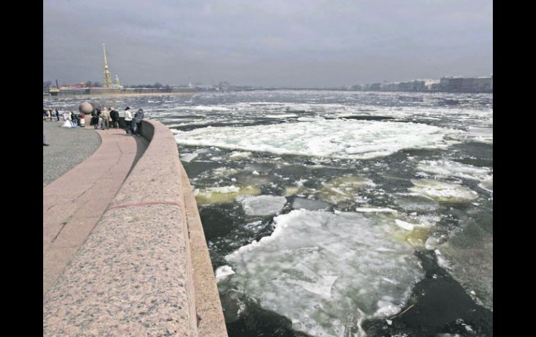 Varias personas observan los bloques de hielo que bajan por el cauce del Río Neva. EFE  /