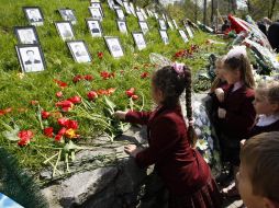 Niños de Ucrania dejan flores junto a las fotos de la víctimas del desastre nuclear. REUTERS  /