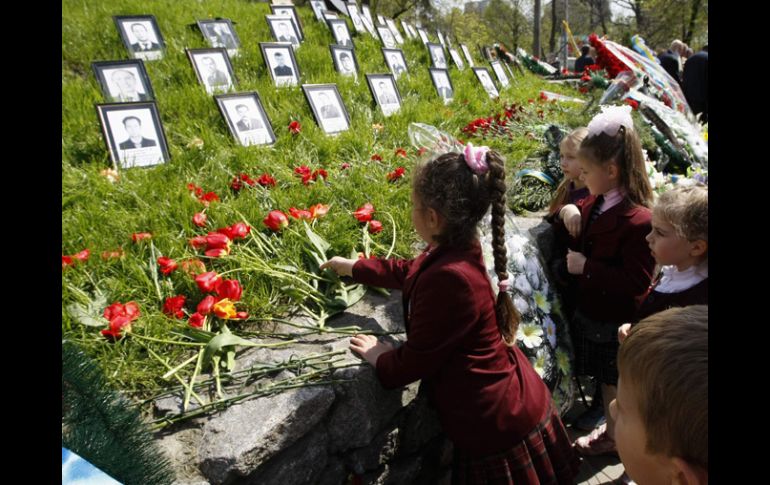 Niños de Ucrania dejan flores junto a las fotos de la víctimas del desastre nuclear. REUTERS  /