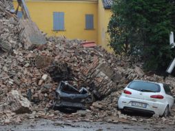 Varios coches quedaron enterrados por los escombros de un edificio destruído tras el terremoto registrado hoy al norte de Italia. EFE  /