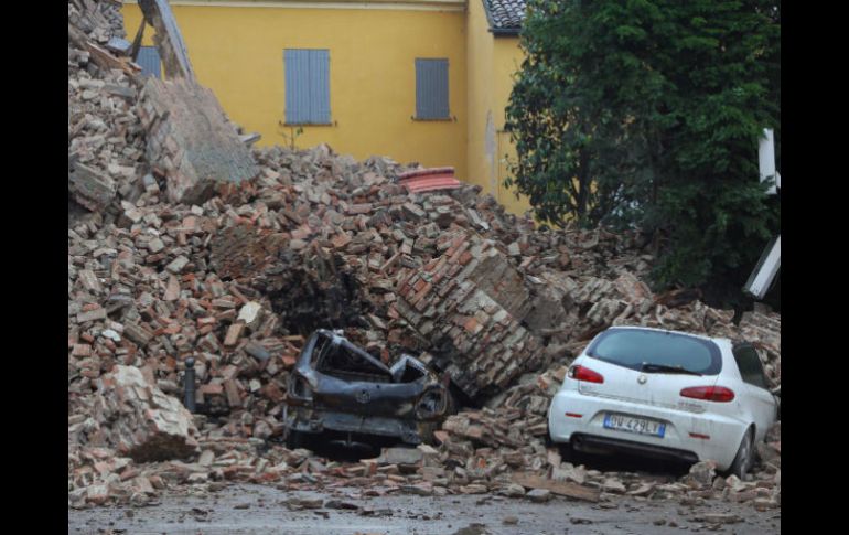 Varios coches quedaron enterrados por los escombros de un edificio destruído tras el terremoto registrado hoy al norte de Italia. EFE  /