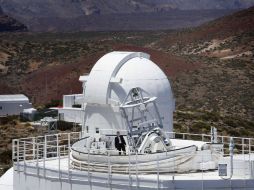 Un hombre posa junto al telescopio Gregor, en Tenerife. Se aprecia plegado el techo retráctil, que permite una mejor refrigeración. AFP  /