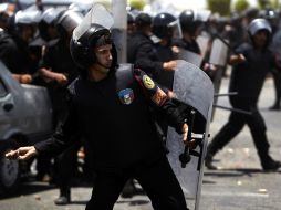 Policías que protegen al ex mandatario en su traslado a la prisión, lanzan piedras a los manifestantes anti-Mubarak . AP  /