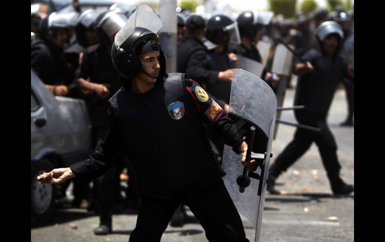 Policías que protegen al ex mandatario en su traslado a la prisión, lanzan piedras a los manifestantes anti-Mubarak . AP  /