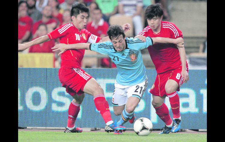 MARCADO. David Silva intenta avanzar ante la pegajosa marca de dos defensas chinos. EFE  /