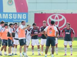 Los futbolistas de Chivas escuchan las instrucciones del técnico John van’t Schip (izquierda) durante la práctica.  /