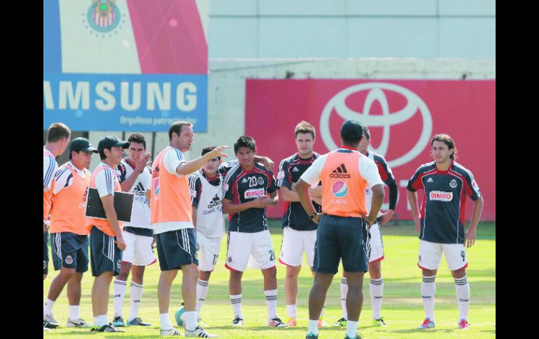 Los futbolistas de Chivas escuchan las instrucciones del técnico John van’t Schip (izquierda) durante la práctica.  /