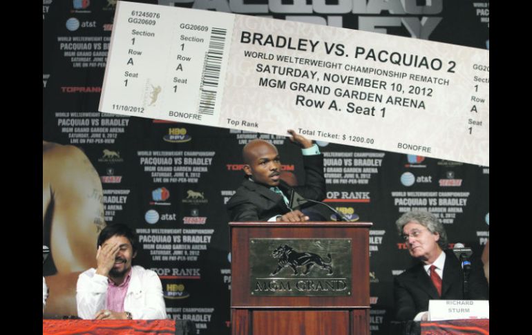 Tim Bradley sostiene un presunto boleto para la “revancha” entre ambos púgiles, mientras que Manny Pacquiao sonríe. AP  /