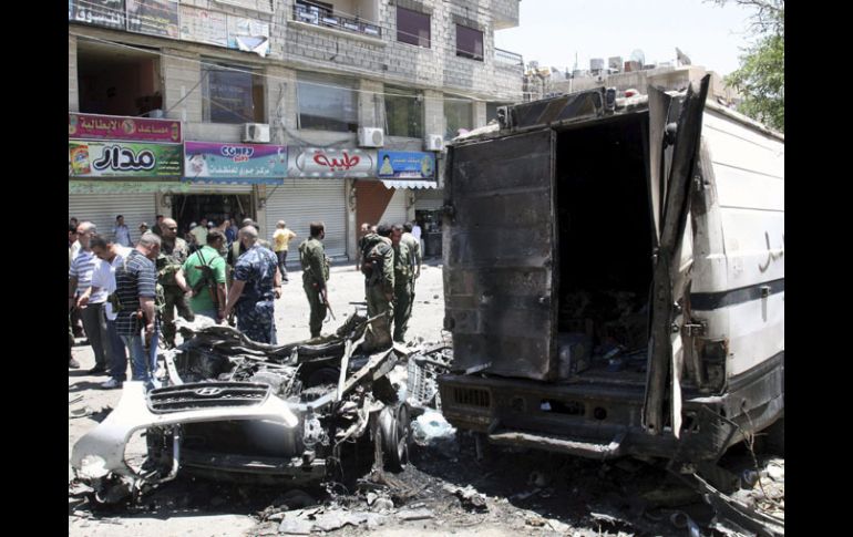 Oficiales de seguridad inspeccionan la zona donde ha explotado un vehículo policial. EFE  /