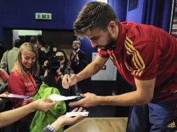 Al finalizar la rueda de prensa Piqué se da tiempo para firmar algunos autógrafos. AP  /