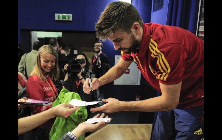 Al finalizar la rueda de prensa Piqué se da tiempo para firmar algunos autógrafos. AP  /