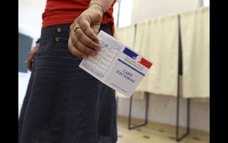 Una mujer muestra su tarjeta electoral antes de ejercer su derecho al voto en Niza. EFE  /