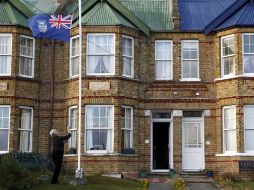 Una mujer izando la bandera de las Islas Malvinas frente a la puerta de su casa, en Stanley (Islas Malvinas). EFE  /