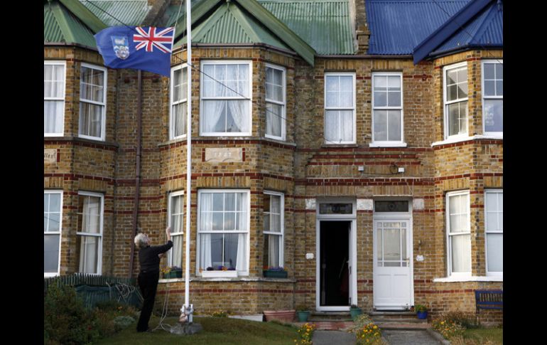 Una mujer izando la bandera de las Islas Malvinas frente a la puerta de su casa, en Stanley (Islas Malvinas). EFE  /