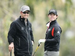 Rory McIlroy (der.), el campeón defensor, charla con el australiano Adam Scott.  /