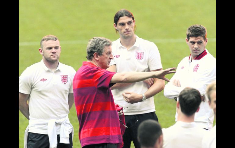 Rooney (i) escucha las indicaciones del técnico Roy Hodgson (c) durante el reconocimiento de la cancha donde hoy juegan. REUTERS  /