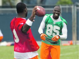 Chad Ochocinco bromea con David Garrard (de espaldas) durante la práctica de los Delfines. AP  /