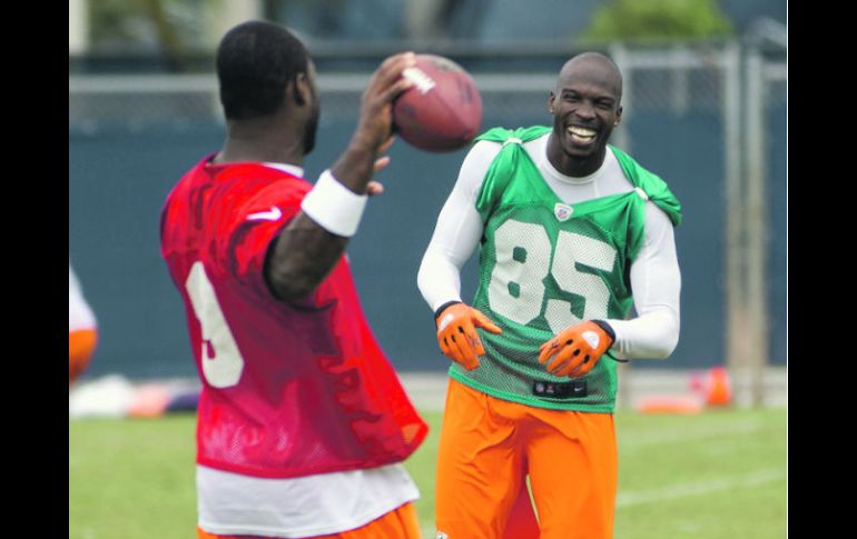 Chad Ochocinco bromea con David Garrard (de espaldas) durante la práctica de los Delfines. AP  /