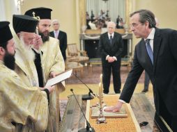 Antonis Samarás, pone su mano sobre la Biblia mientras presta juramento en el Palacio Presidencial, en Atenas. AFP  /