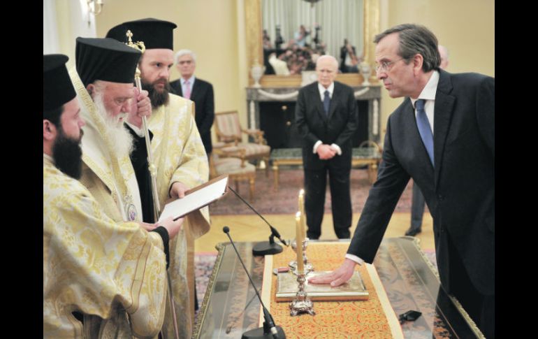 Antonis Samarás, pone su mano sobre la Biblia mientras presta juramento en el Palacio Presidencial, en Atenas. AFP  /