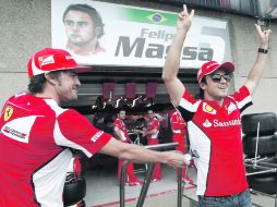 BIEN VIGILADO. Fernando Alonso bromea con su compañero Felipe Massa afuera del pit de Ferrari. AP  /