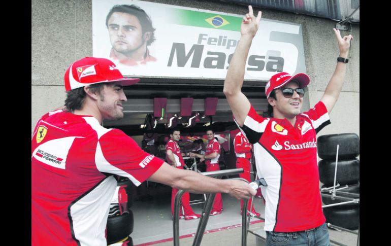 BIEN VIGILADO. Fernando Alonso bromea con su compañero Felipe Massa afuera del pit de Ferrari. AP  /