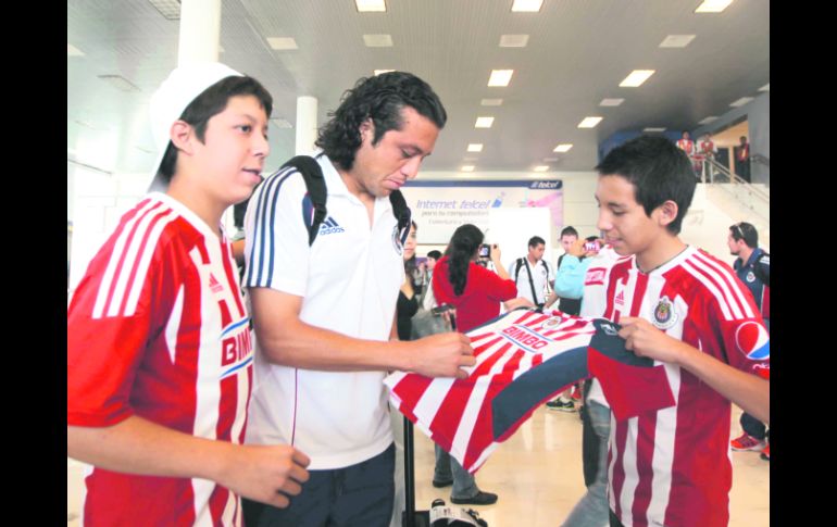 El defensa central de Chivas, Héctor Reynoso atiende a los aficionados del Rebaño en el Aeropuerto Internacional de Guadalajara.  /