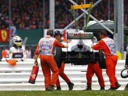 Sergio Pérez (izq) observa como es sacado su vehículo de a pista en Silverstone. AP  /