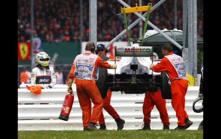 Sergio Pérez (izq) observa como es sacado su vehículo de a pista en Silverstone. AP  /