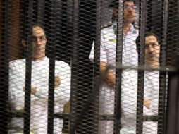 Gamal (i) y Alaa (d), hijos del ex presidente Mubarak, tras los barrotes durante su juicio en la Academia de Policía de El Cairo. EFE  /