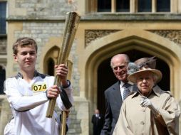 Reina Isabel II y el duque de Edimburgo observar como el atleta Phillip Wells sostiene la llama olímpica. ESPECIAL  /