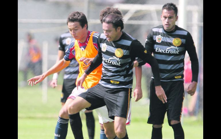 El defensa de Leones, Juan Manuel García Zavala (centro), trata de quitarle el balón al delantero chiva, Érick “Cubo” Torres. CORTESÍA  /