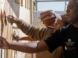 Como parte de la celebración, habitantes de Sudáfrica reparan un muro de una escuela. AP  /