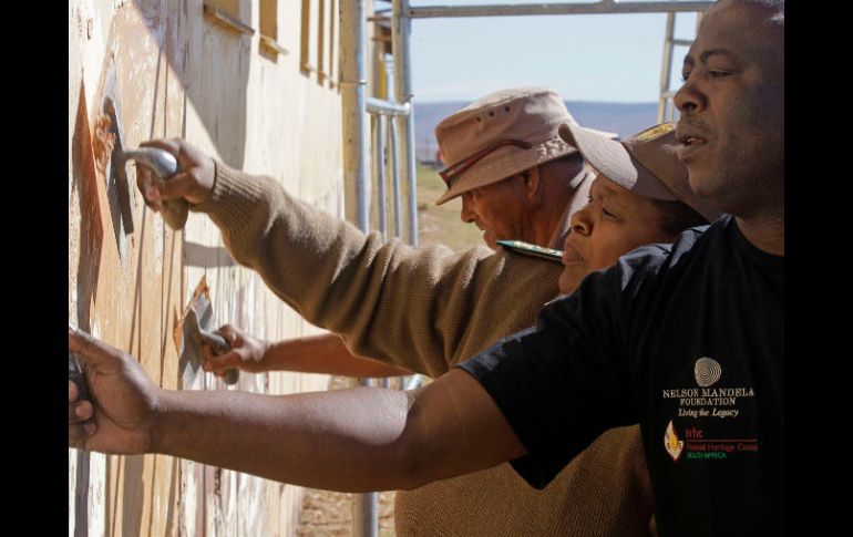 Como parte de la celebración, habitantes de Sudáfrica reparan un muro de una escuela. AP  /