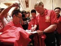 Sir Alex Ferguson da autógrafos a fanaticos en China a la llegada del Manchester United. AP  /