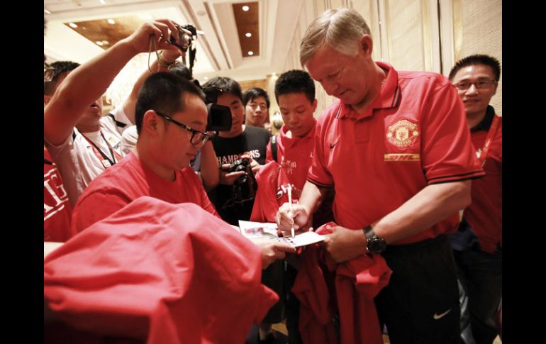 Sir Alex Ferguson da autógrafos a fanaticos en China a la llegada del Manchester United. AP  /