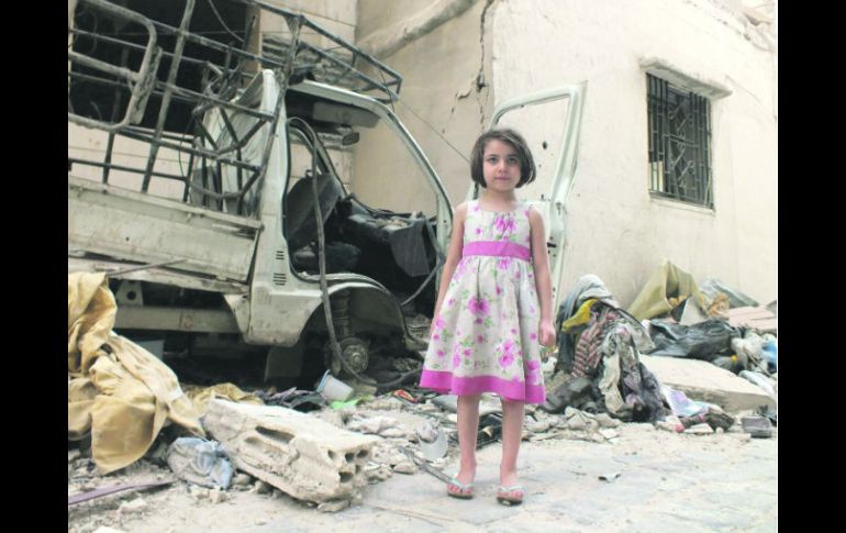 Una niña siria posa para el fotógrafo Yazen Homsy en un marco de destrucción en un barrio de la ciudad de Homs. REUTERS  /