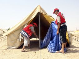 Voluntarios de la Media Luna Roja montan tiendas de campaña para alojar a los refugiados sirios. EFE  /