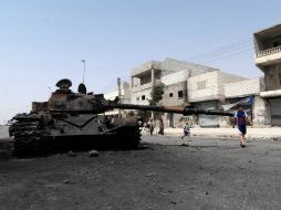 Varios niños juegan cerca a un tanque del ejército sirio destruido tras un enfrentamiento con rebeldes, en una calle de Alepo. EFE  /